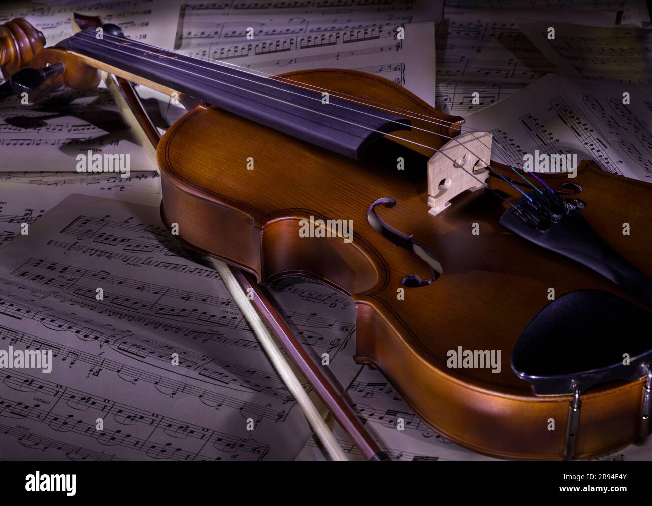 Violino disteso su spartiti con fiocco Foto Stock