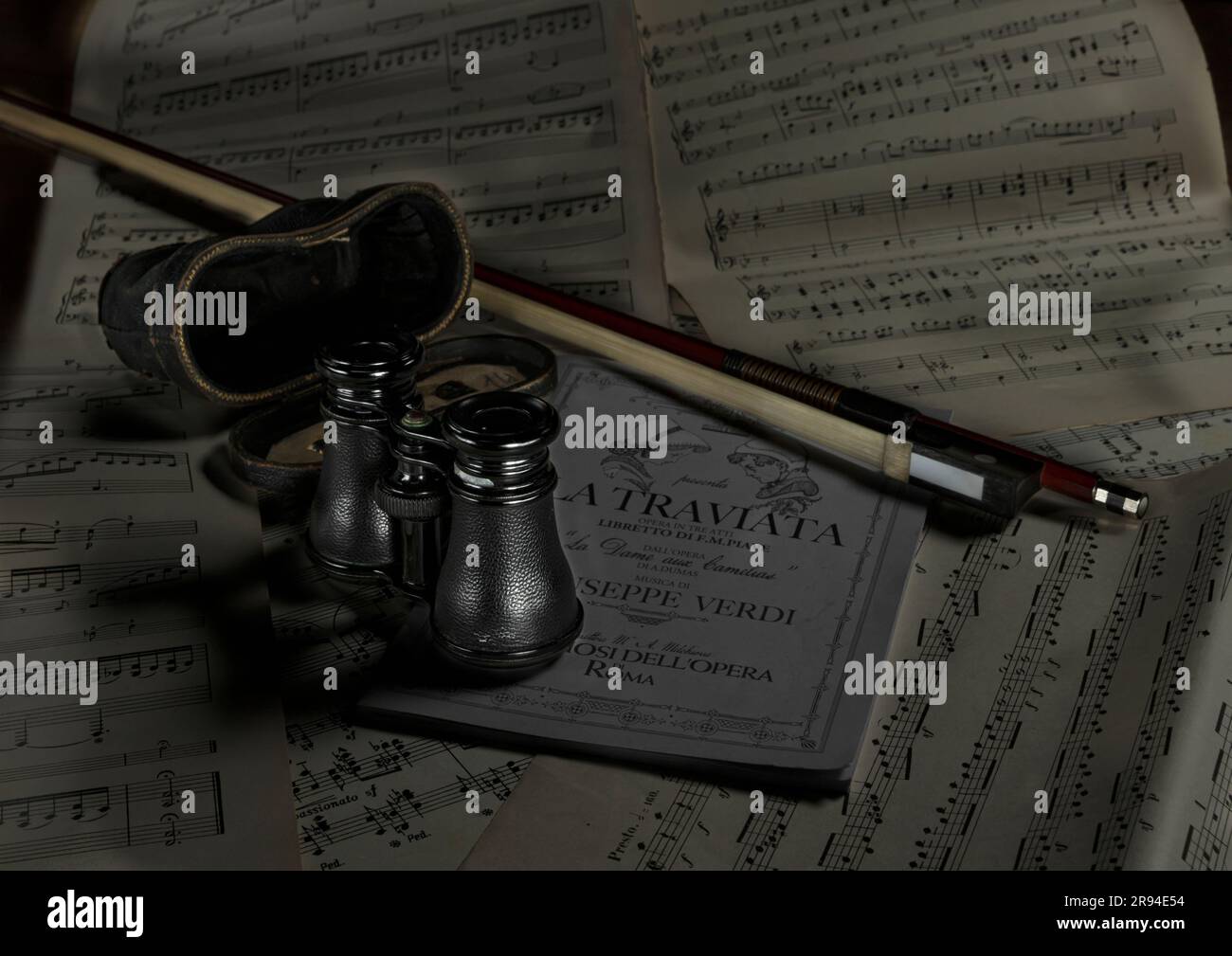Bicchieri d'opera seduti su spartiti musicali con programma d'opera e arco per violino Foto Stock