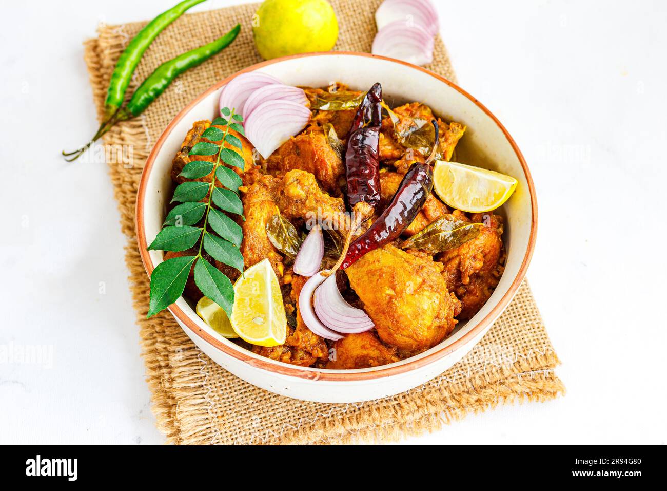 Pollo fritto piccante in stile indiano del sud con foglie di curry, limone, peperoni rossi e peperoni verdi Foto Stock
