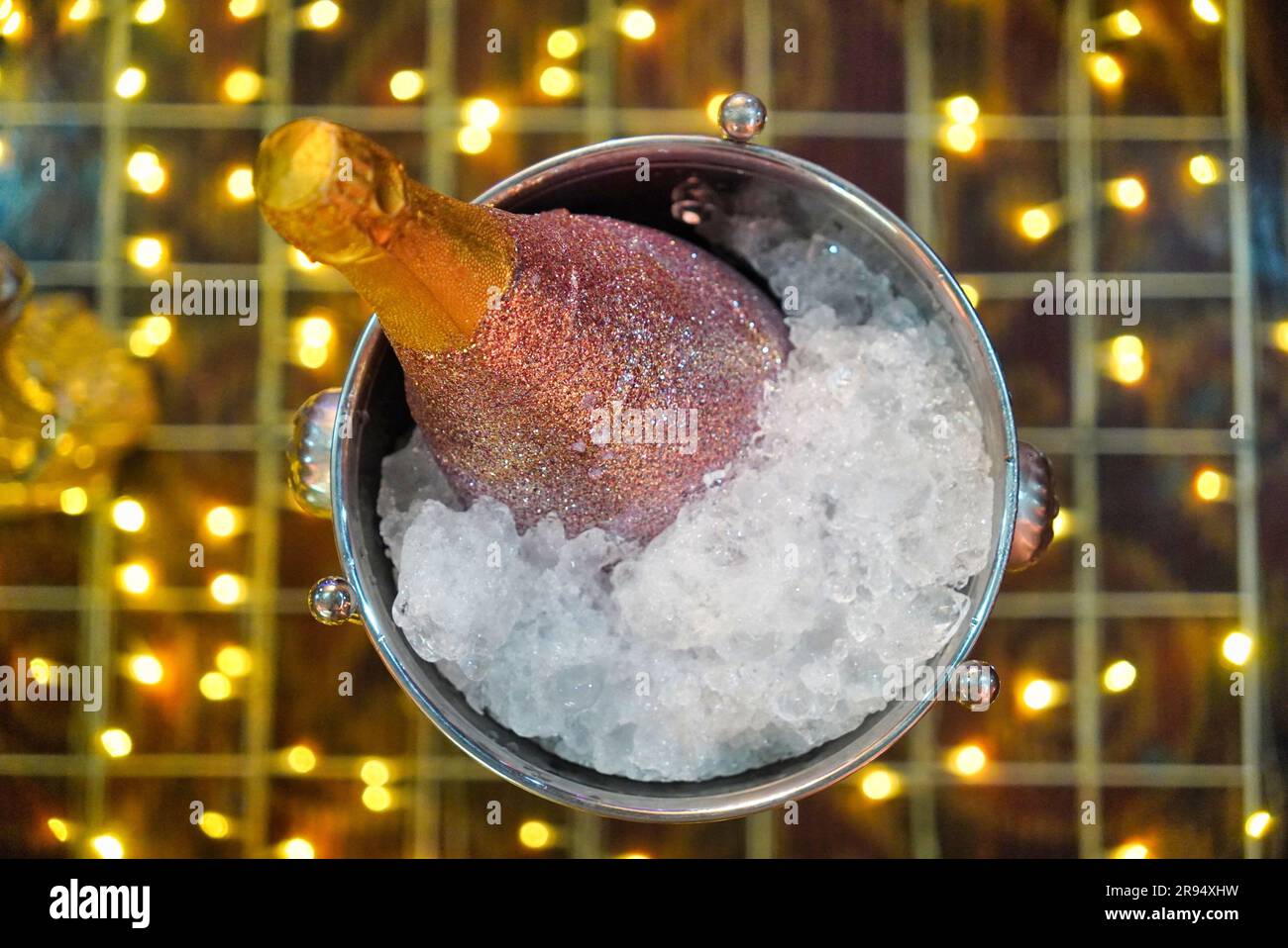 Una bottiglia ghiacciata di champagne dorato in un secchio di metallo, circondato da cubetti di ghiaccio, pronto per essere aperto e gustato Foto Stock