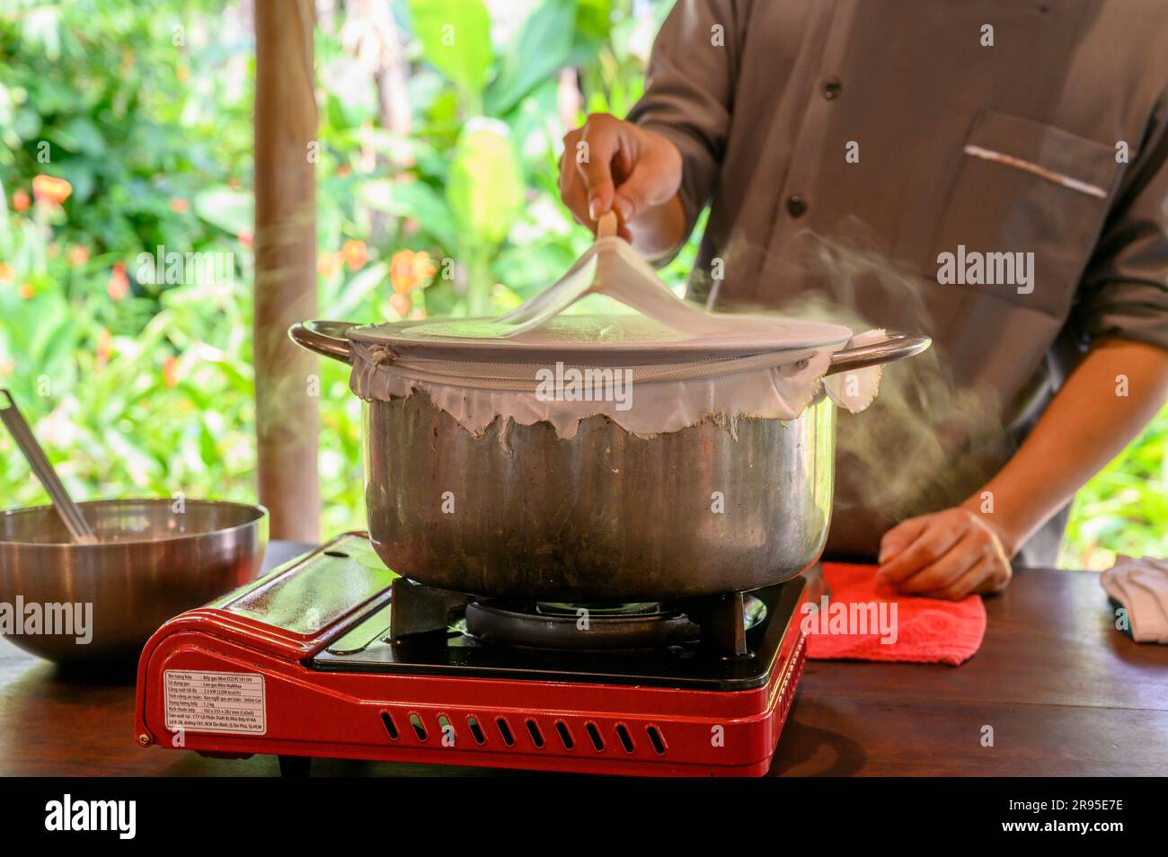 Chef e tutor dimostrano come cucinare la carta di riso utilizzata per panini e spaghetti presso la scuola di cucina Red Bridge alla periferia di Hoi An, in Vietnam. Foto Stock