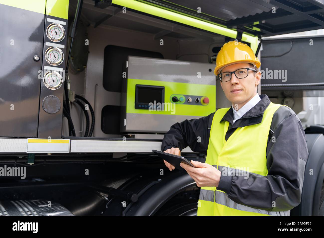 Lavoratore con un tablet digitale che utilizza le macchine per l'edilizia. Foto Stock