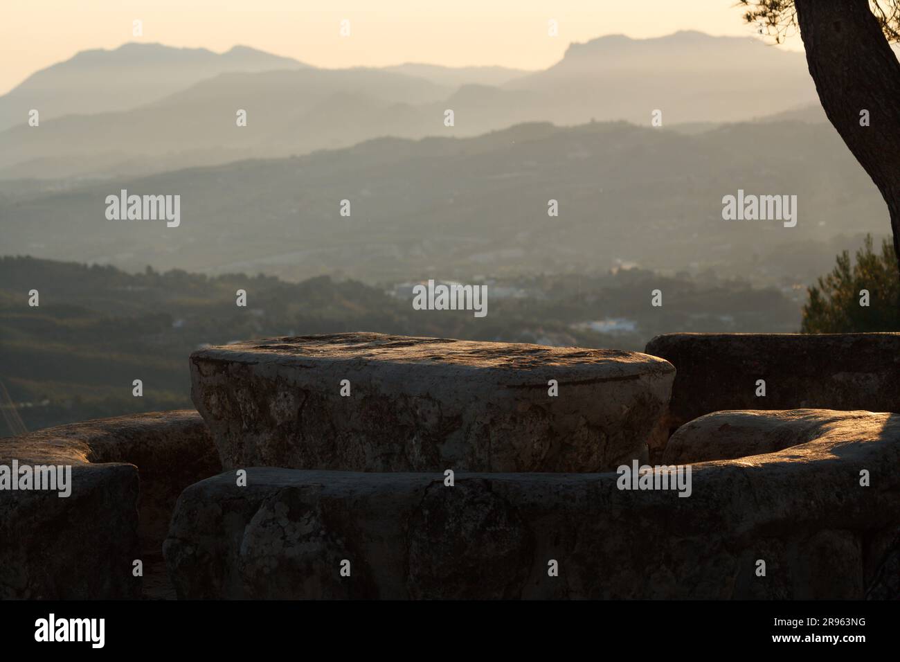 Area picnic in pietra con prima luce al mattino e sfondo con paesaggio sfocato delle montagne all'alba, Alcoy, Spagna Foto Stock