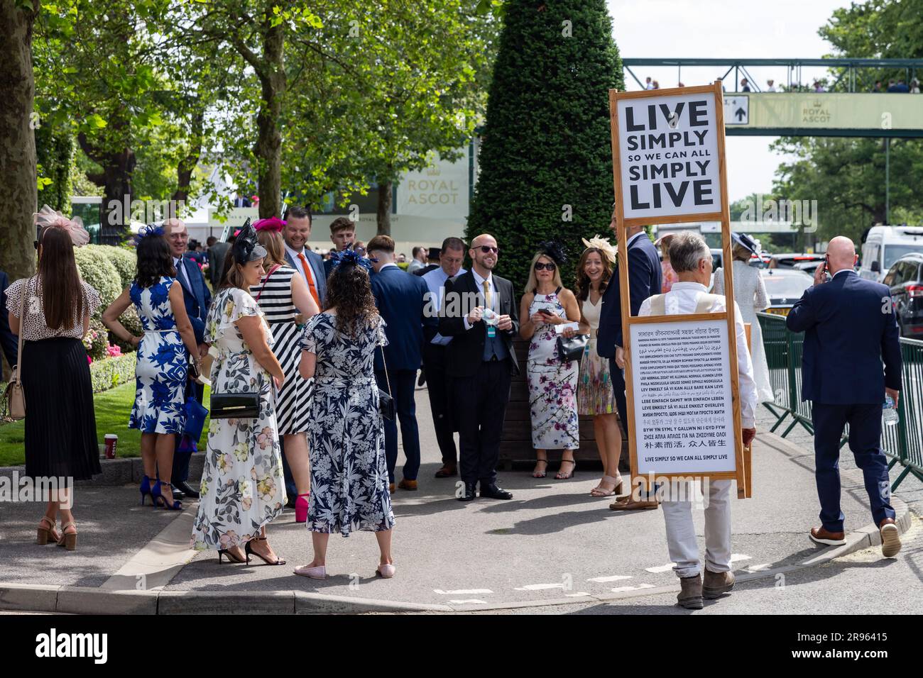 Ascot, Regno Unito. 23 giugno 2023. Un uomo cammina all'esterno dell'ippodromo di Ascot con una tavola con la scritta "Live Simply so we CAN all Simply Live", mentre gli automobilisti arrivano per il quarto giorno di Royal Ascot. Ogni recinzione Royal Ascot ha un codice di abbigliamento diverso, con il più rigoroso applicabile al Royal Enclosure, ma alcune restrizioni si applicano a tutti gli involucri. Crediti: Mark Kerrison/Alamy Live News Foto Stock