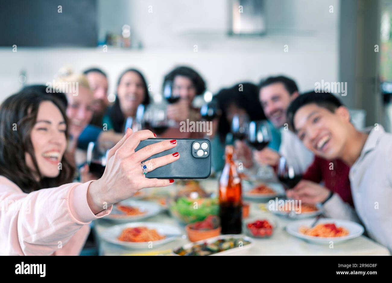 Gruppo di amici che fanno selfie durante il pranzo al chiuso Foto Stock