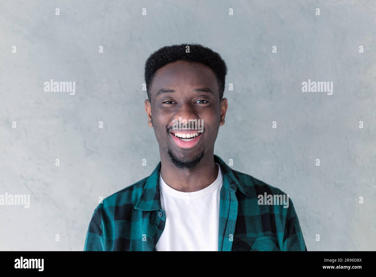 Bellissimo giovane uomo dalla pelle scura e non rasata che ride mostrando i suoi denti bianchi e dritti. Espressioni ed emozioni positive del volto umano Foto Stock