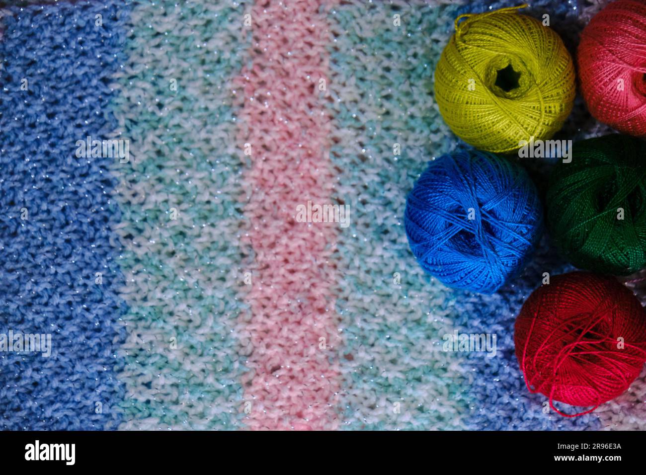Filati per uncinetto. Diverse palline di lana multicolore di filo su sfondo  a righe rosa-azzurro a uncinetto. Concetto di hobby di ricci fatti a mano  da Foto stock - Alamy