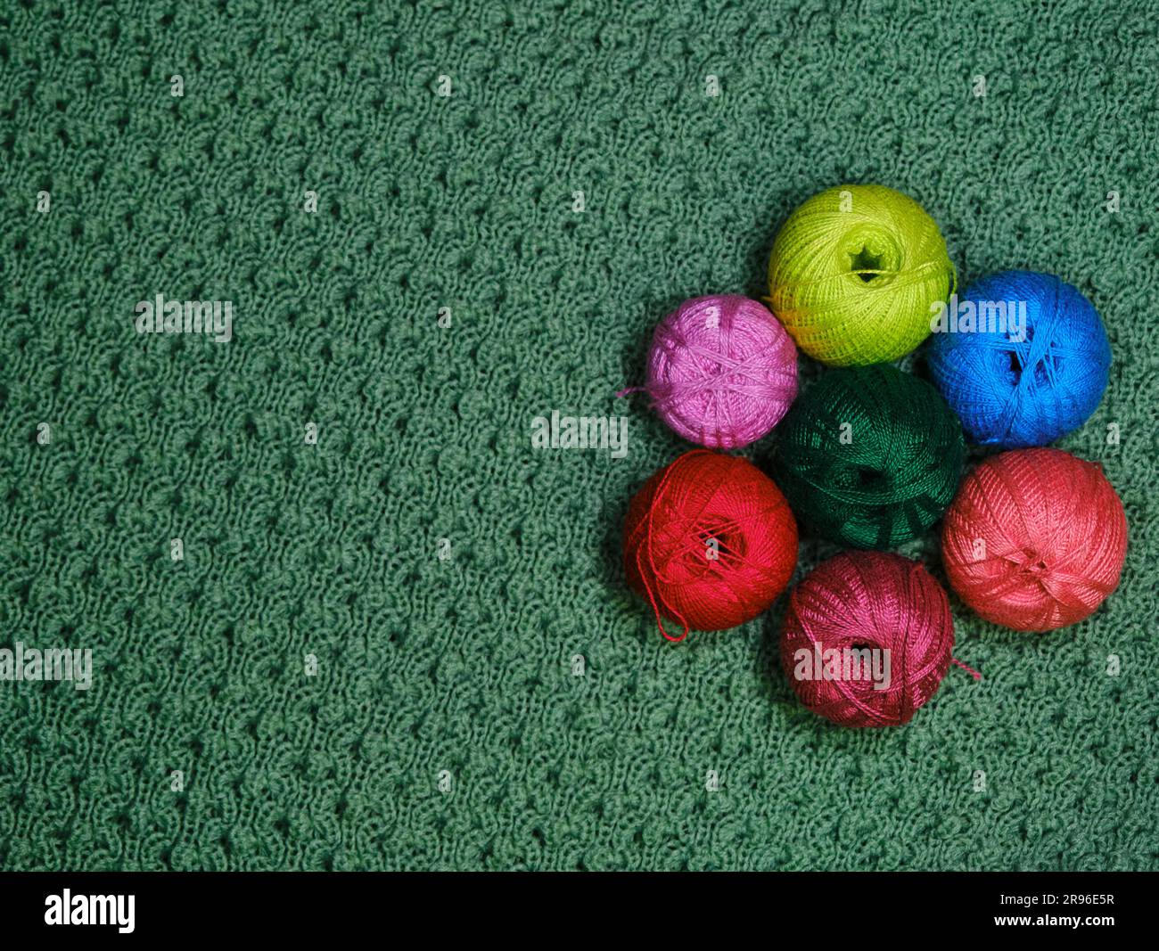 Filati per uncinetto. Diverse palline di lana multicolore di filo su uno  sfondo verde a uncinetto. Concetto di hobby di ricci fatti a mano da casa.  In alto Foto stock - Alamy