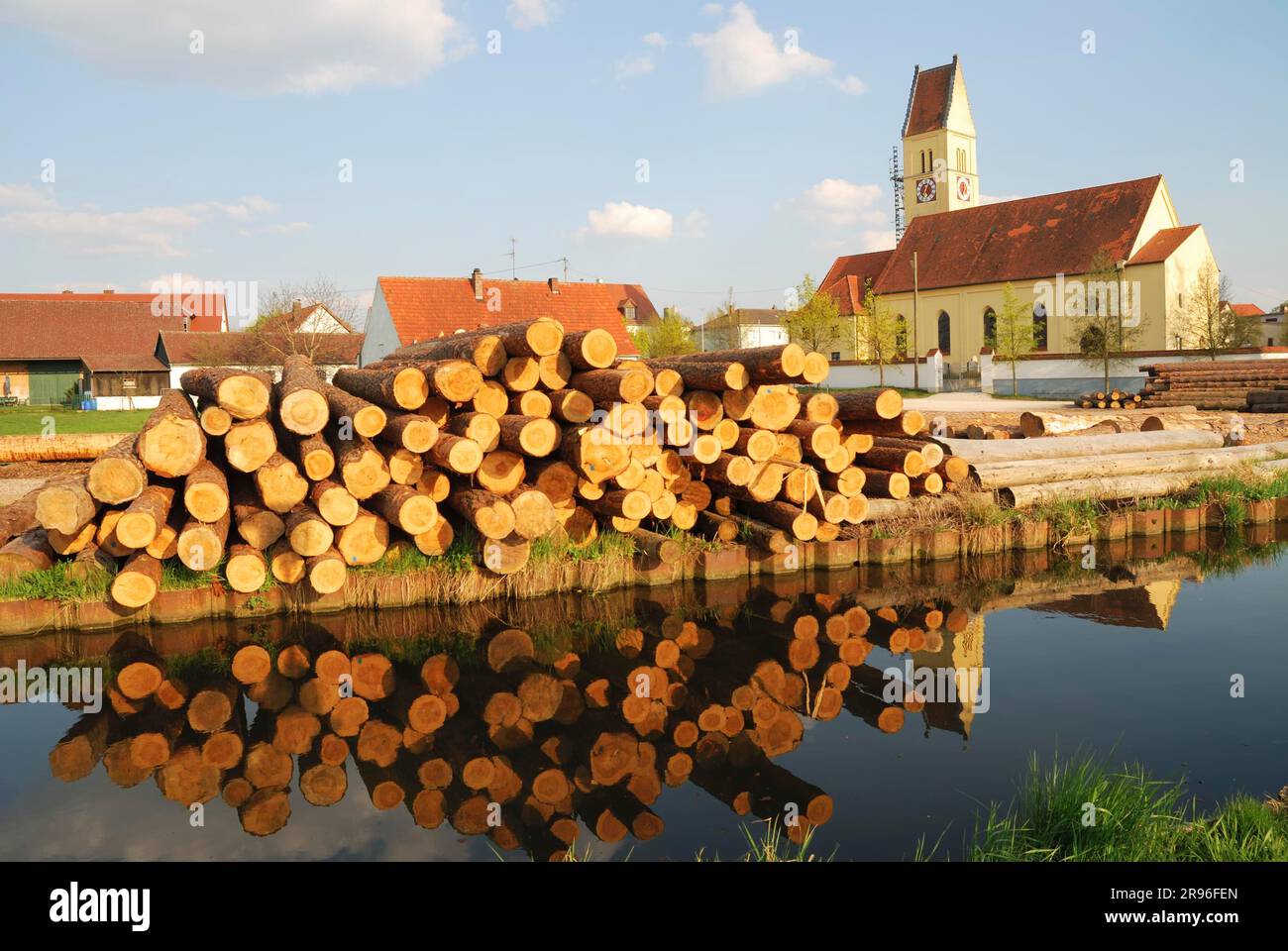 Tronchi di legno, chiesa e acqua in Baviera, Germania Foto Stock