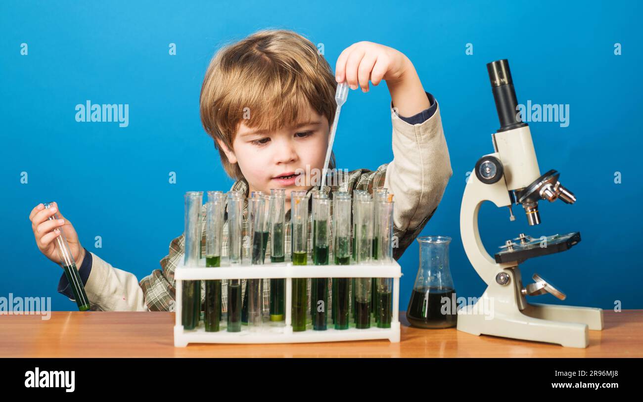 Esperimento educativo. Ragazzo con provette e microscopio in classe scolastica. Giornata della conoscenza. Studio di biologia e chimica dei bambini. Scienza, istruzione e. Foto Stock