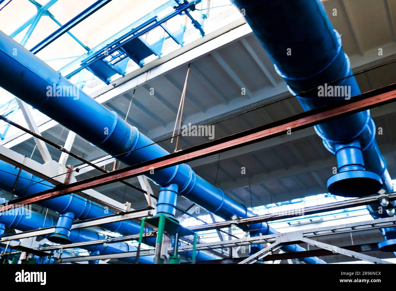 Il soffitto dell'officina presso la raffineria di costruzione di macchine per l'industria chimica e petrolchimica con tubi in ferro blu grandi di aspirazione e scarico V Foto Stock