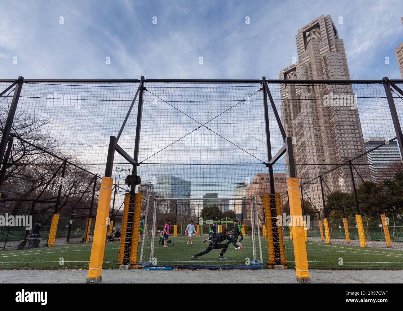 Le persone giocano a calcio a cinque in un campo di calcetto sotto le Tokyo Metropolitan Government Towers a Shinjuku, Tokyo, Giappone. Foto Stock