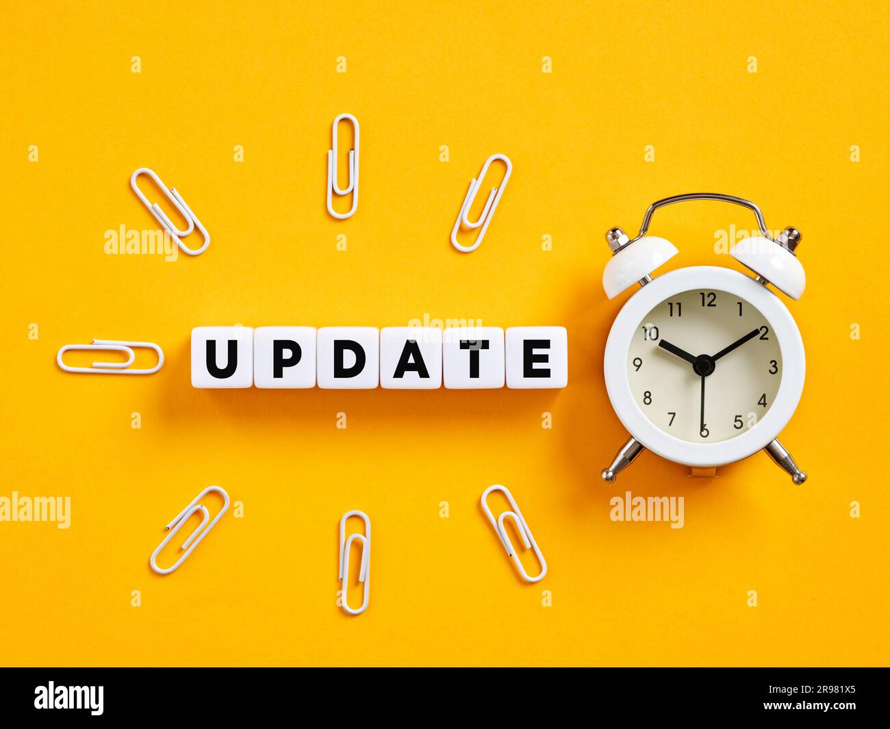 Aggiornamento della parola sui cubi con sveglia e graffette. È il momento di un aggiornamento software. Annuncio di aggiornamento delle notizie. Foto Stock