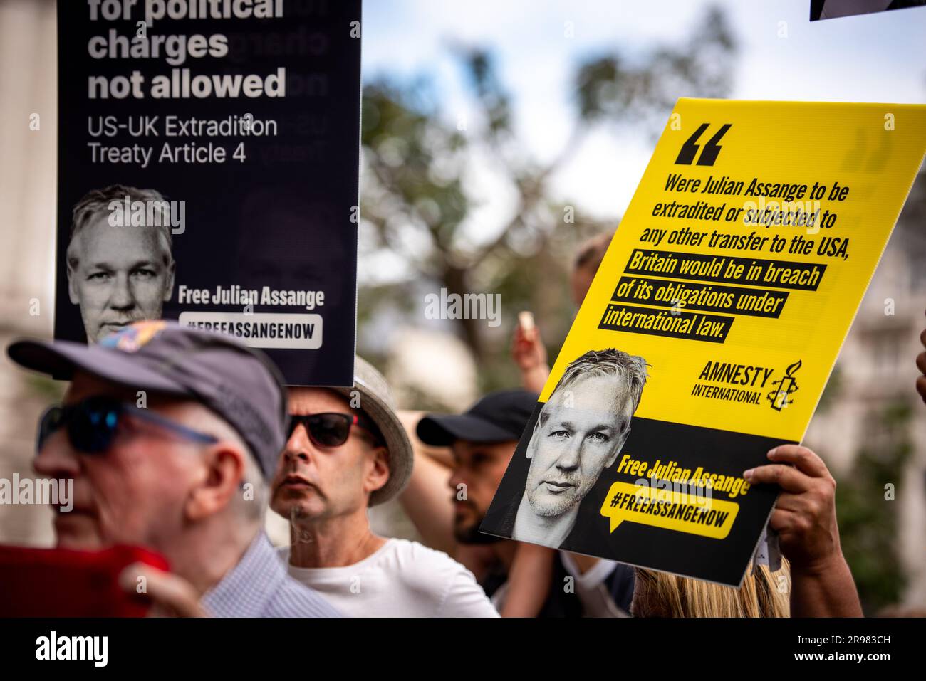 I manifestanti tengono cartelli durante il “qualcosa da dire?” Protesta gratuita di Julian Assange a Parliament Square a Londra. "Qualcosa da dire?" È una scultura in bronzo a grandezza naturale che ritrae tre figure, ognuna in piedi su una sedia dell'artista Davide Dormino. La quarta sedia è vuota perché è la nostra sedia. Quella che ci ha permesso di esprimere noi stessi o semplicemente di stare accanto a Edward Snowden, Julian Assange e Chelsea Manning, che hanno avuto il coraggio di dire di no all'intrusione della sorveglianza globale e alle bugie che portano alla guerra. Foto Stock