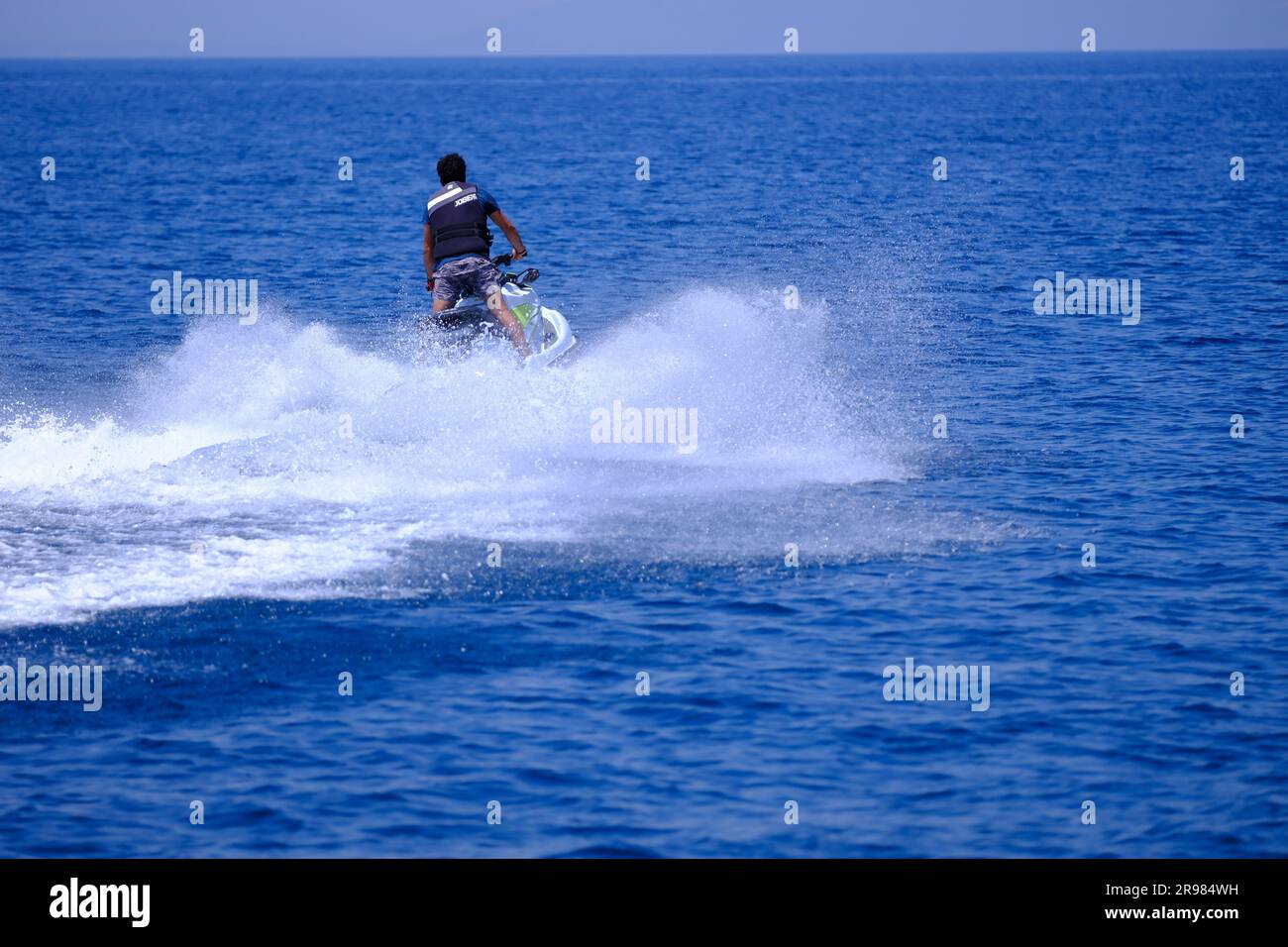 Giovane con la barba in moto d'acqua in una soleggiata giornata estiva Foto Stock