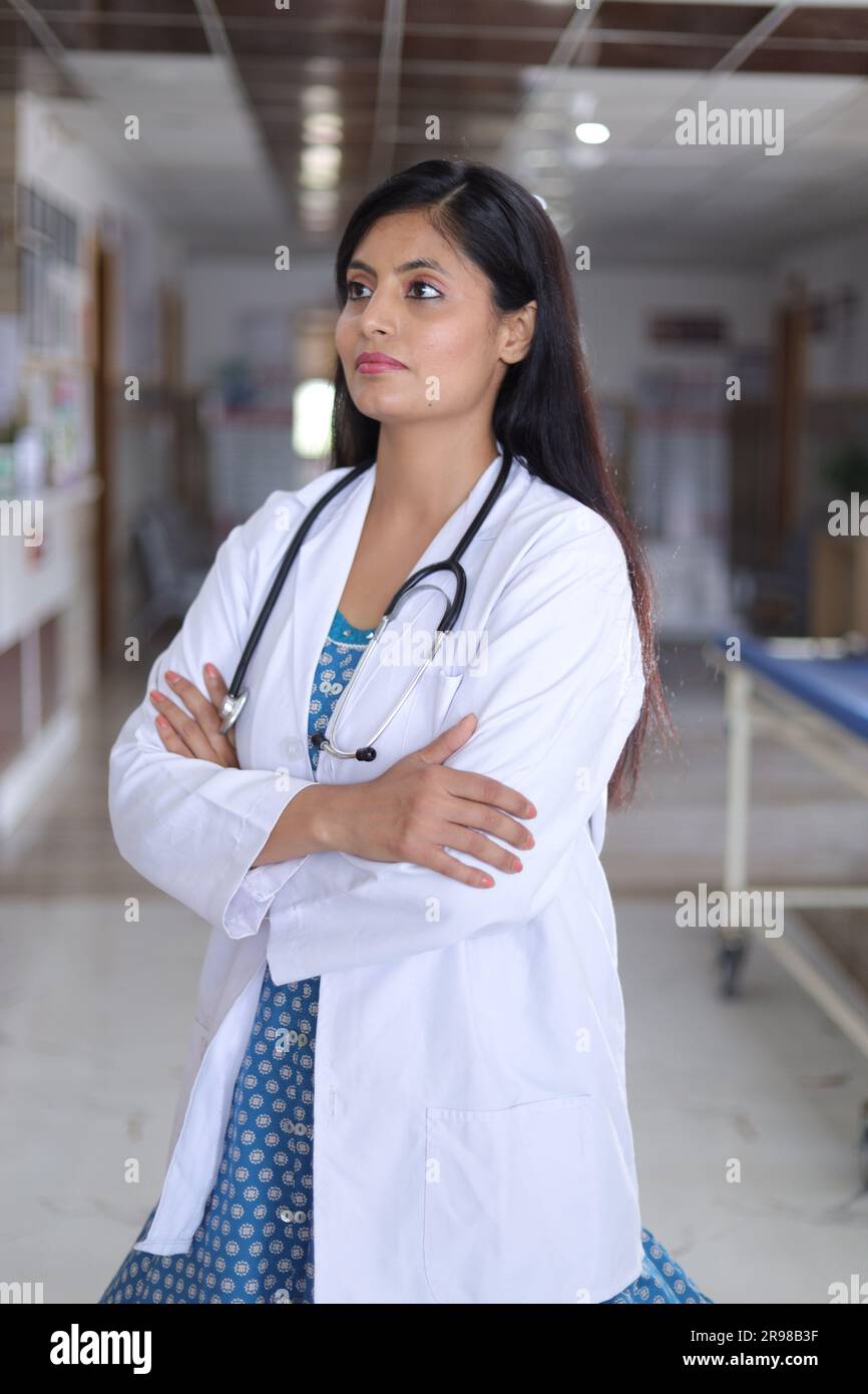 Ritratto di una donna sicura di sé, anziana, medico con le braccia incrociate. Buon medico in camice bianco da laboratorio in piedi nel corridoio dell'ospedale. Foto Stock
