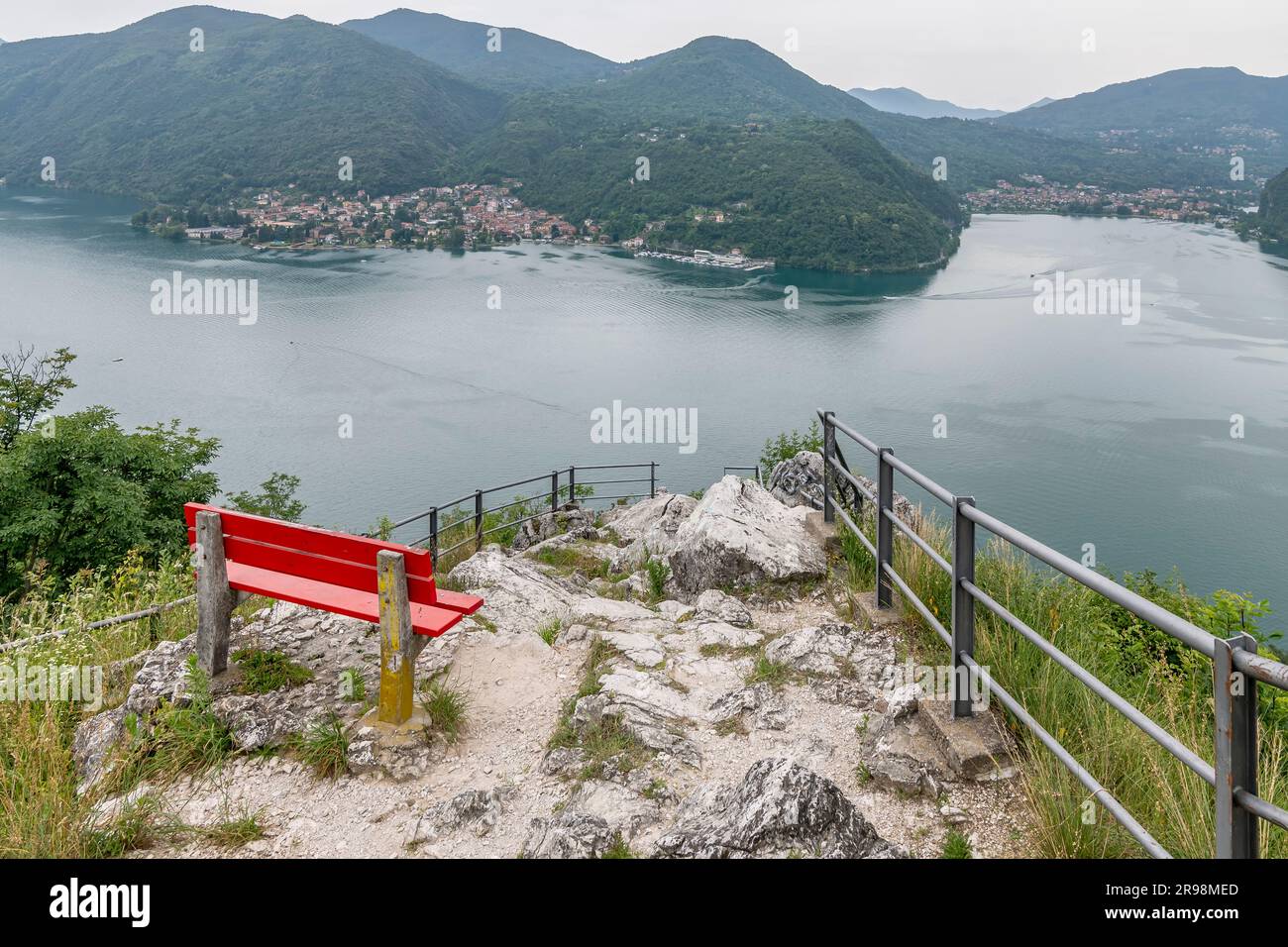 Una panchina rossa nel punto panoramico chiamato Sasso delle parole, con un'incredibile vista dalla cima del Lago di Lugano, Svizzera Foto Stock