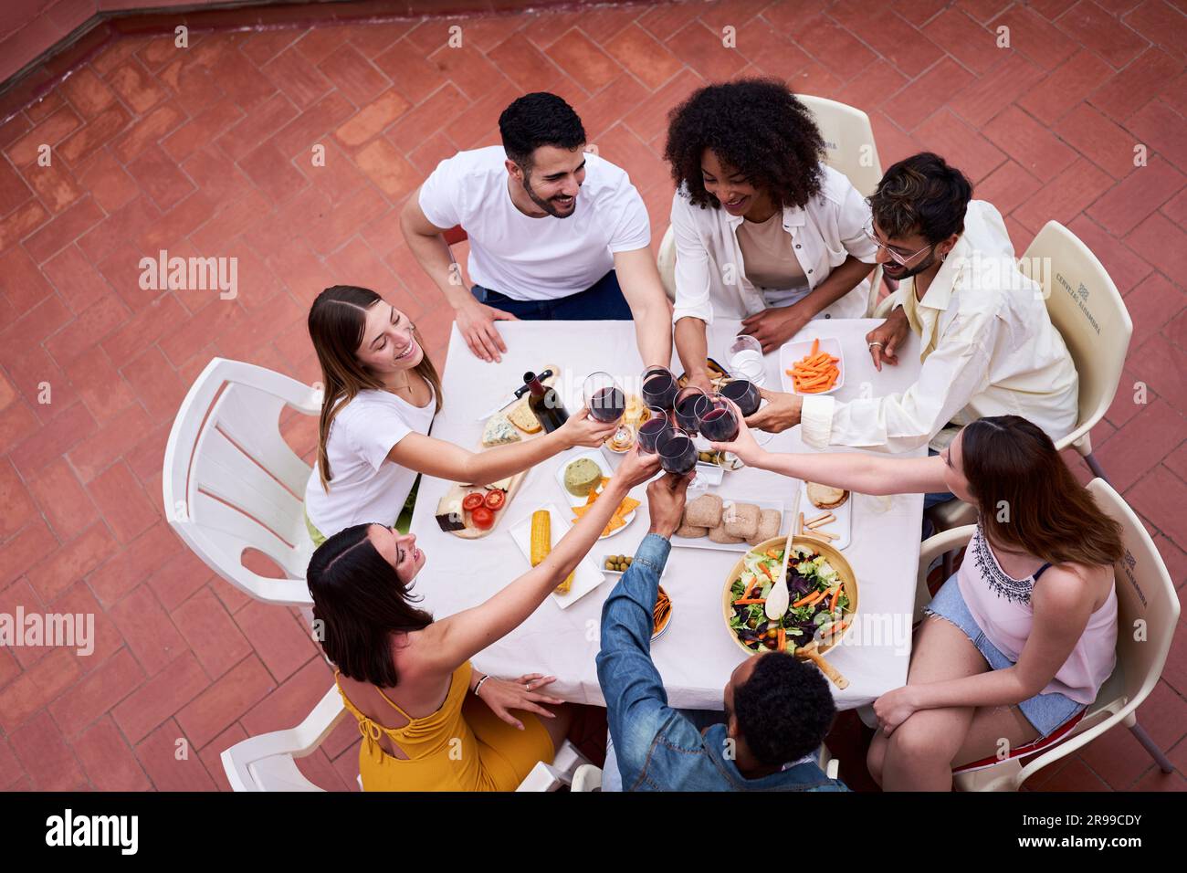 Vista dall'alto di un felice gruppo di amici che brindano con vino rosso all'aperto in una terrazza per festeggiare. Foto Stock