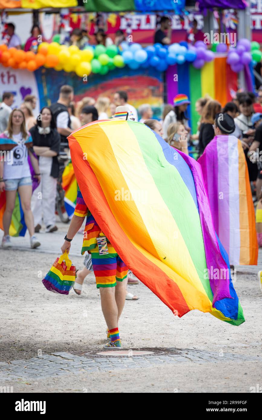 Monaco di Baviera, GERMANIA - 24 giugno 2023: People at the Parade at Christopher Street Day CSD a Monaco di Baviera. Un tizio che porta una bandiera arcobaleno sulla testa. Foto Stock