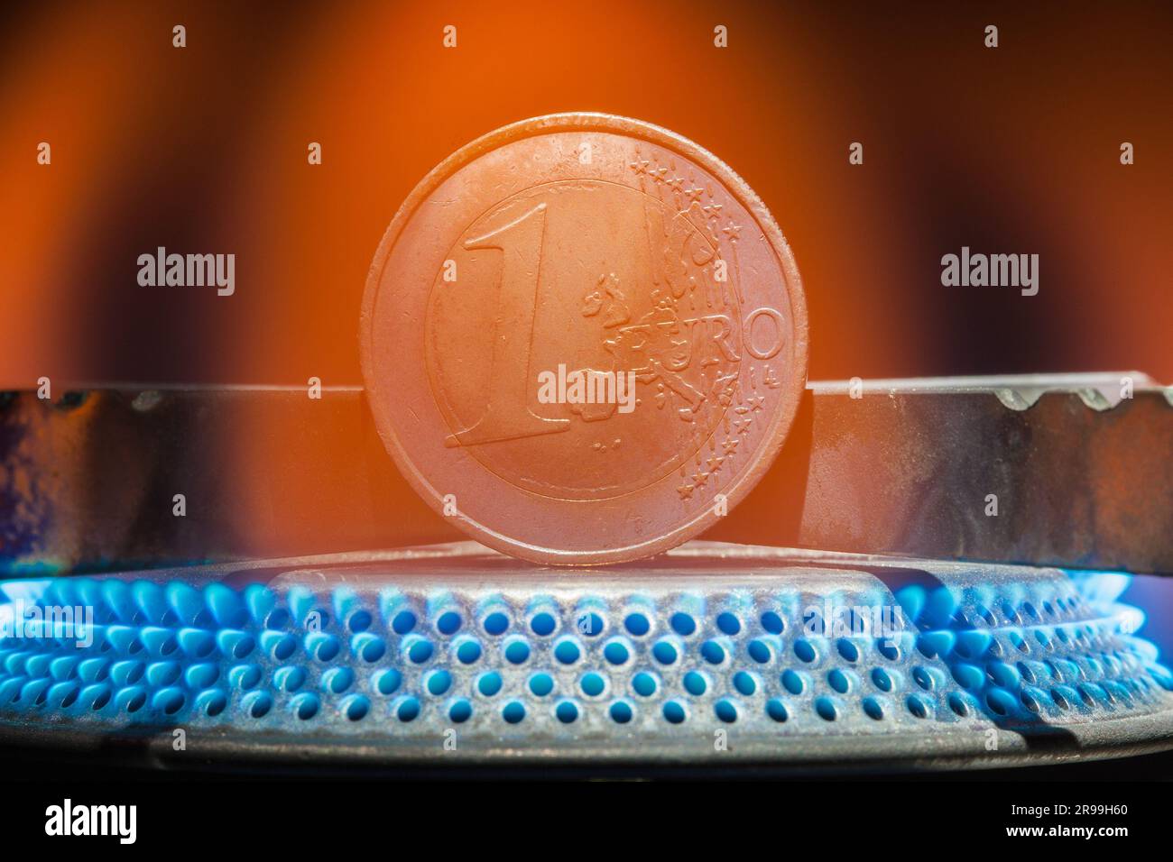 Moneta in euro sopra una fiamma di gas. I prezzi elevati dell'energia per il gas, il petrolio e l'elettricità fanno brillare i consumatori. Foto Stock