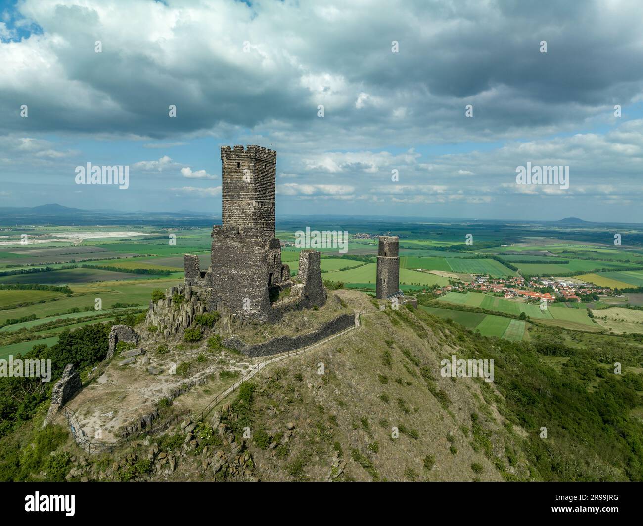 La vista aerea dei resti del castello medievale di Hazmburk con una torre circolare e rettangolare si trova in cima a questo punto di trekking a picco basso con sceni Foto Stock
