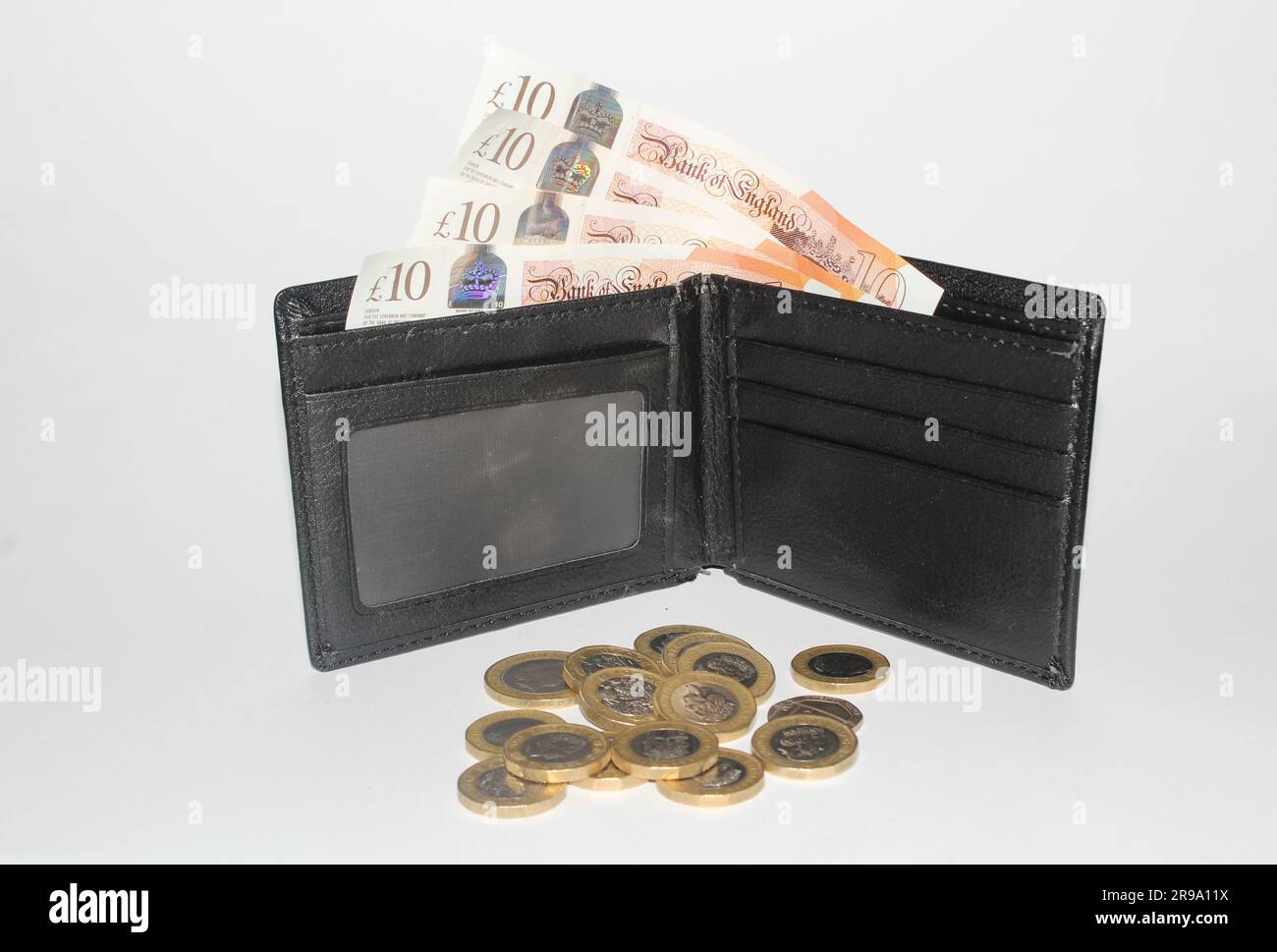 Un portafoglio pieno di monete e banconote inglesi del regno, con una sterlina di monete e banconote da £10 e £5 sterline primo piano Foto Stock