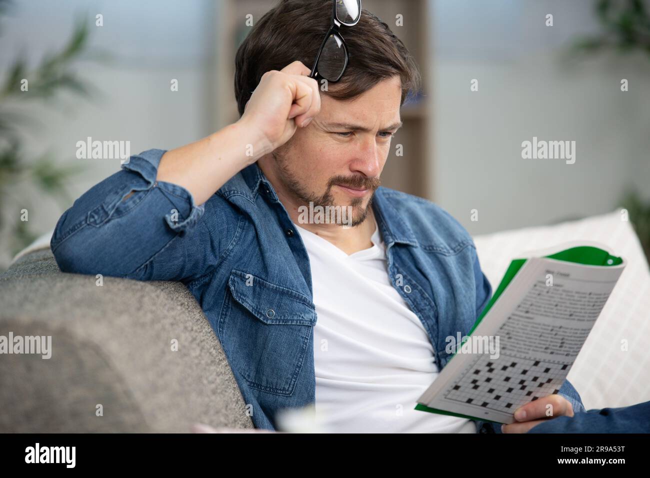 giovane uomo seduto facendo un puzzle crossword Foto Stock