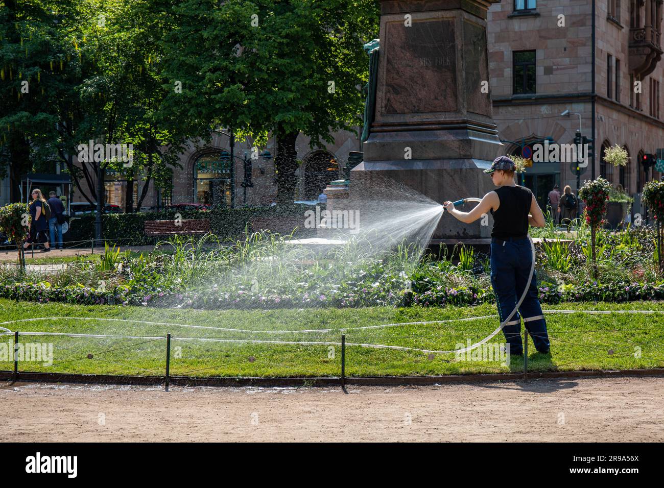 Durante una soleggiata giornata estiva a Helsinki, Finlandia, gli addetti alla manutenzione dei parcheggi che innaffiano erba e piante all'Esplanade Park Foto Stock