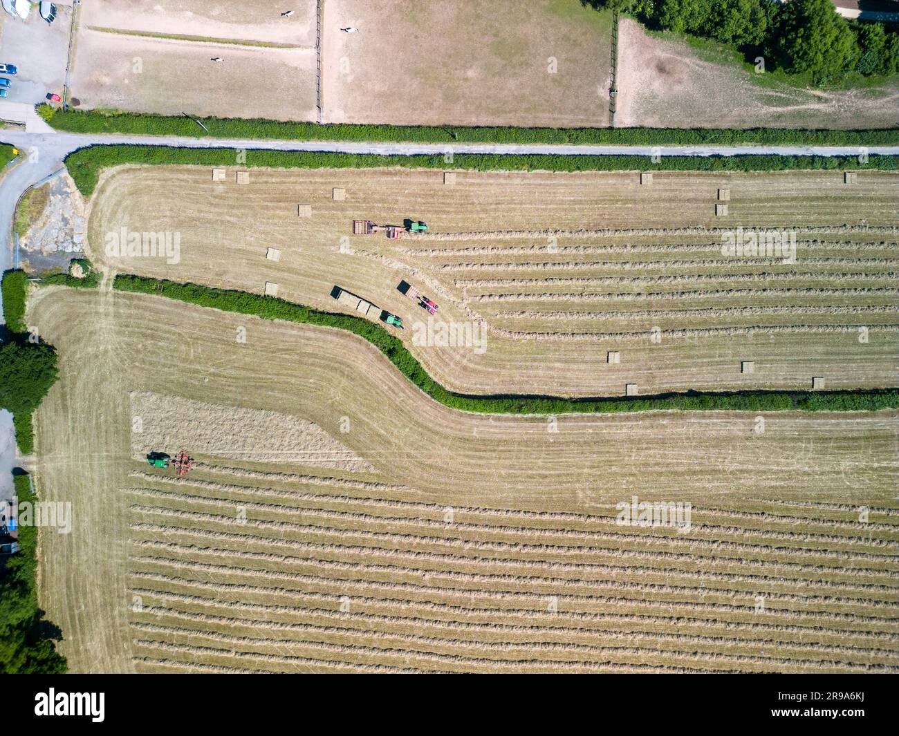 Taglio e raccolta del fieno con pinza per balle per macchine agricole in estate, vista aerea. Foto Stock