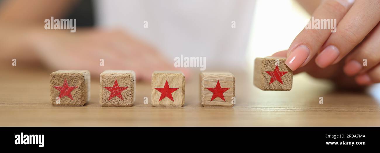 Mano femmina che tiene cubo di legno con stella rossa Foto Stock