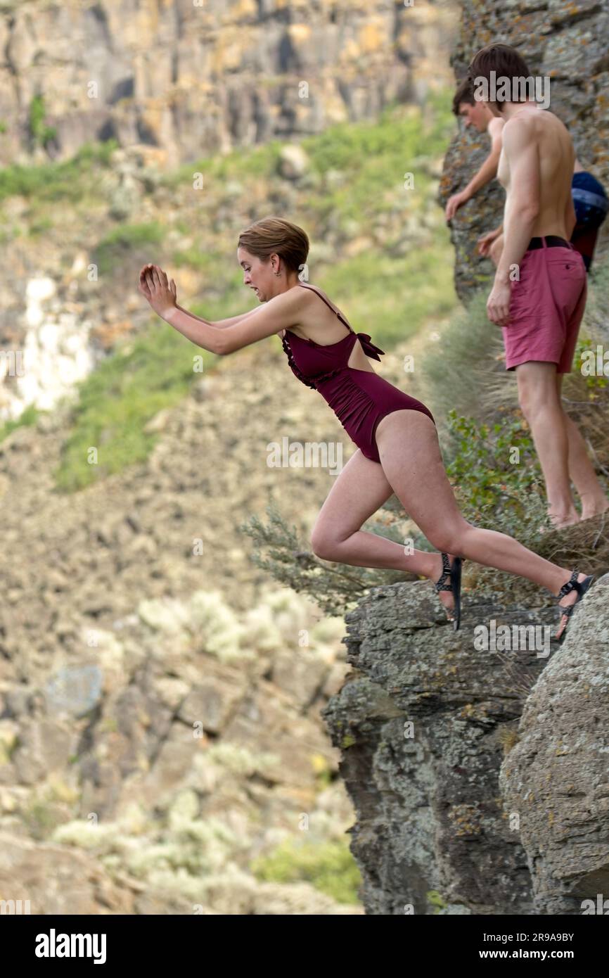 Una giovane donna inizia a saltare da una scogliera nell'acqua sottostante a Twin Falls, Idaho. Foto Stock