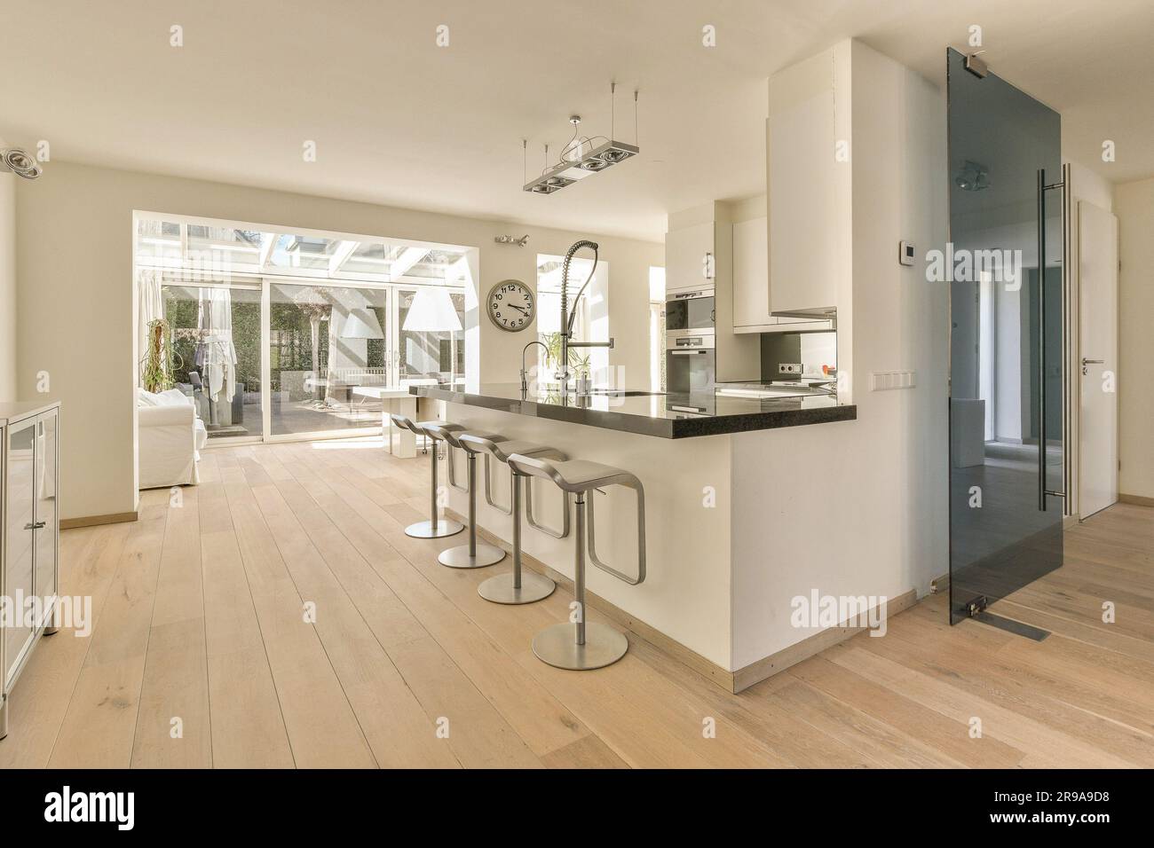 una cucina e un'area pranzo in una casa con pavimenti in legno duro, pareti bianche e pavimento in legno su entrambi i lati Foto Stock