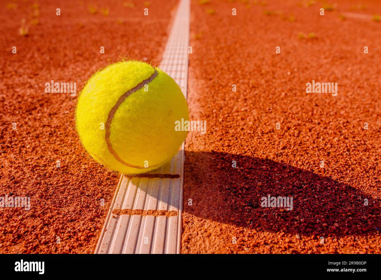 Pallina da tennis gialla che tocca la linea sul campo di argilla rossa Foto Stock