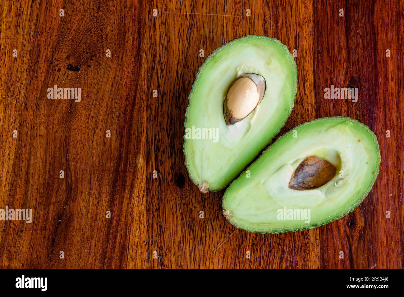 Avocado tagliato a metà su un tavolo scuro Foto Stock