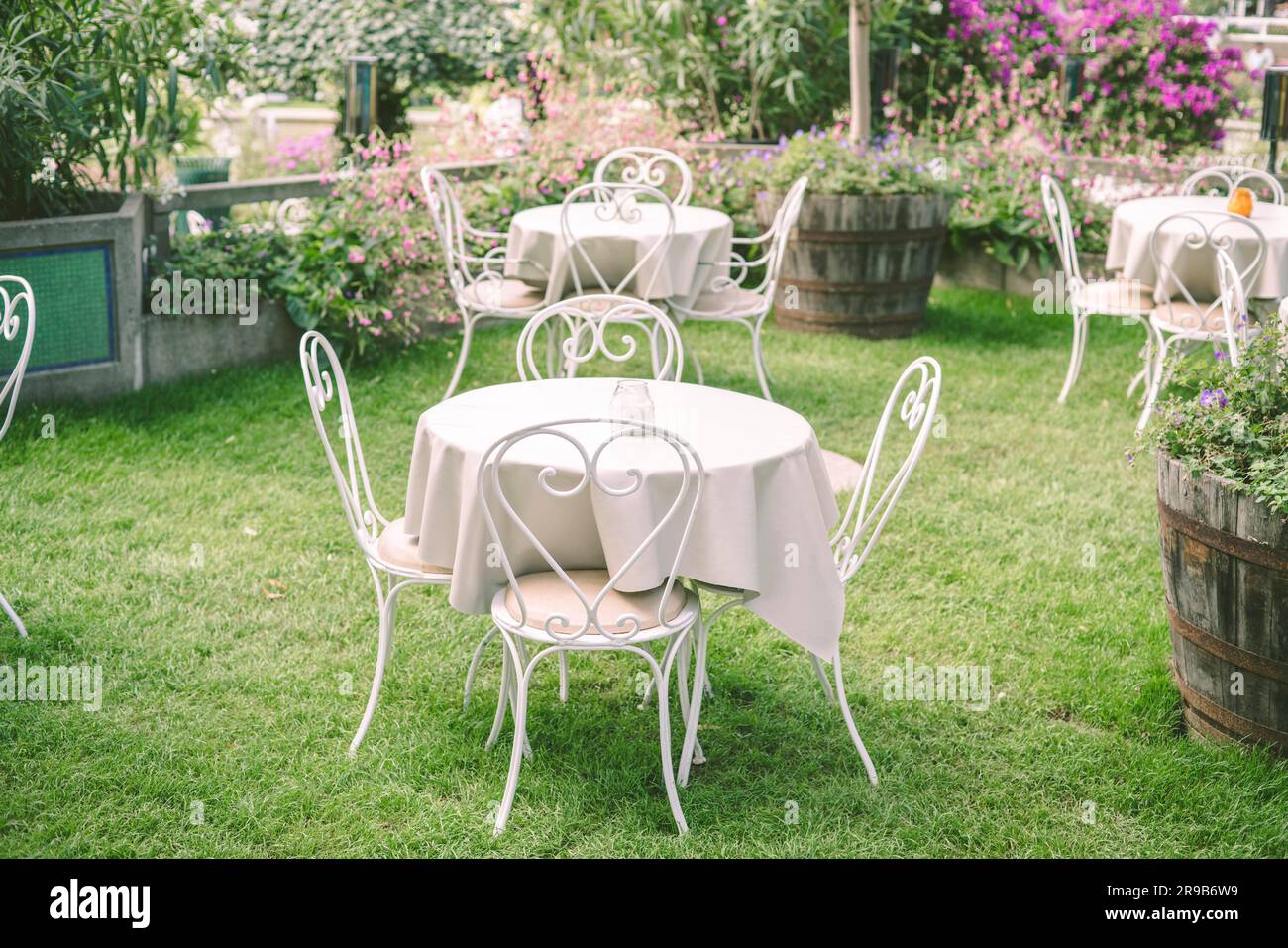 Romantico giardino con mobili vintage e tovaglia circondato da fiori Foto Stock