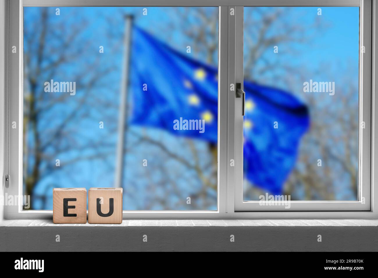 Segno dell'UE in una finestra con la bandiera dell'Unione europea fuori sventolando nel vento Foto Stock