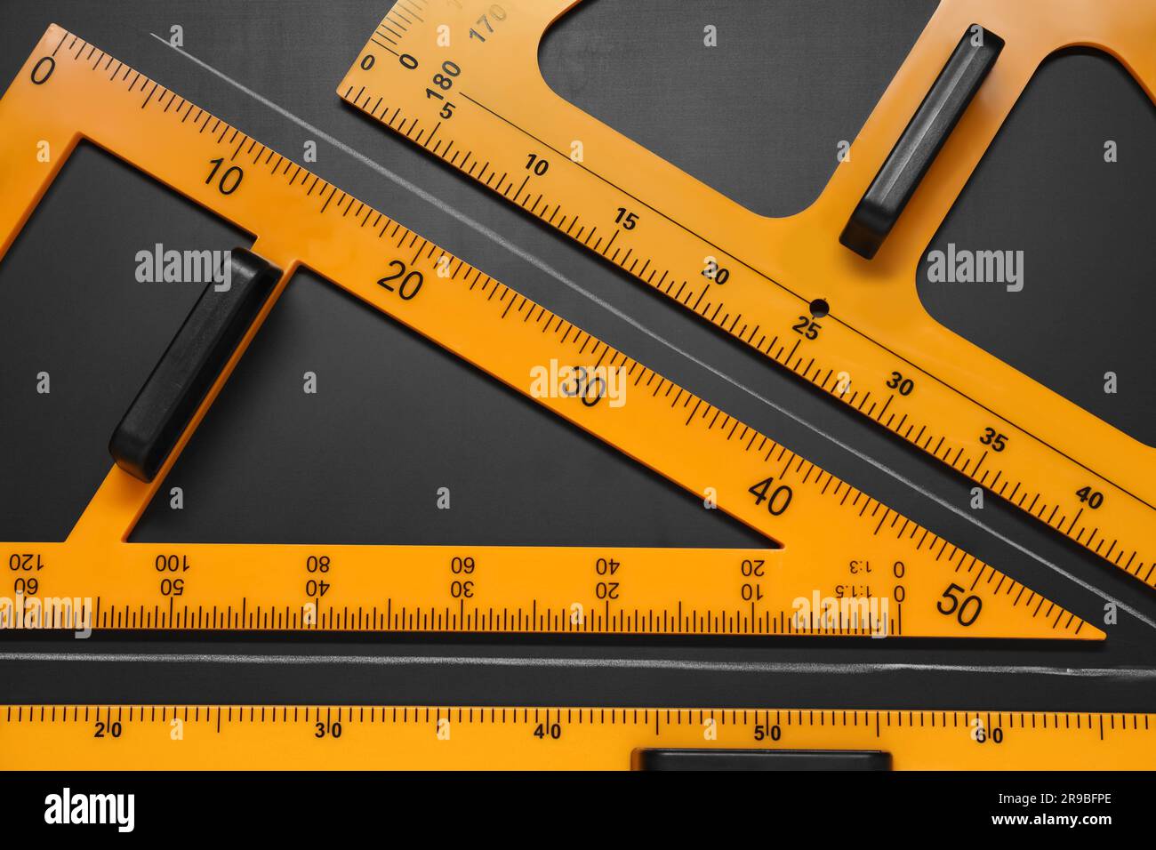 Triangolo, goniometro, righello e angolo acuto disegnato su tavolo nero, piatto Foto Stock