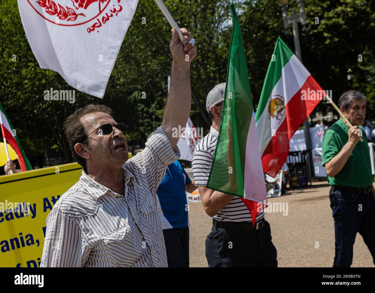 Un manifestante sventola la bandiera dell'Organizzazione Popolare Mojahedin dell'Iran (PMOI). Il quartier generale del PMOI a Camp Ashraf 3, Albania, è stato razziato dalla polizia albanese il 20 giugno 2023 a seguito delle accuse che il gruppo di opposizione ha lanciato attacchi informatici contro potenze straniere e ha violato i termini del suo asilo. Il membro del partito Ali Mostashari, onorato alla protesta, è stato ucciso durante il raid. (Foto di Collin Mayfield/Sipa USA) credito: SIPA USA/Alamy Live News Foto Stock