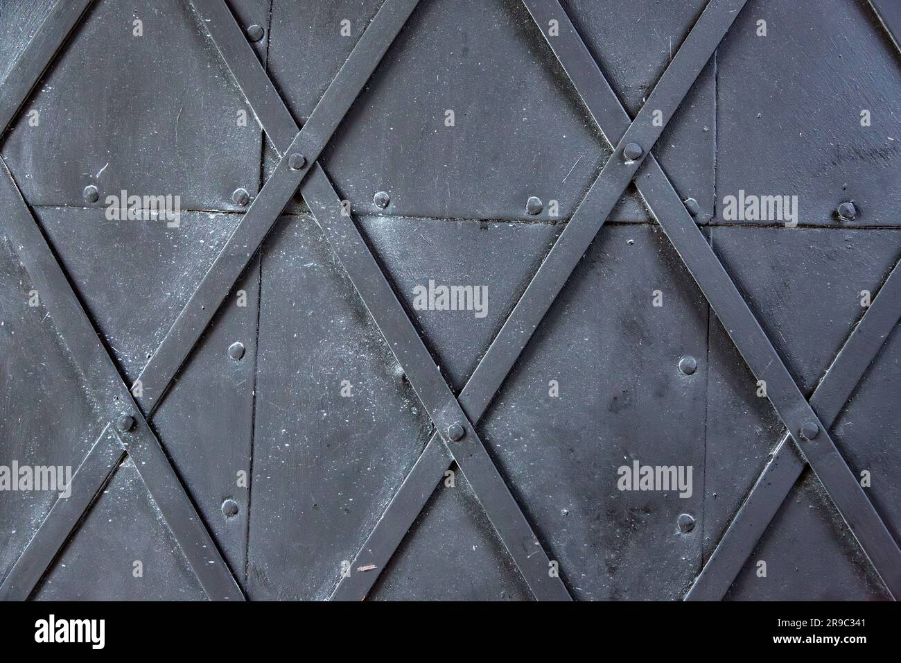 Dettagli ravvicinati sullo sfondo di una porta metallica con strisce e chiodi a rombi Foto Stock