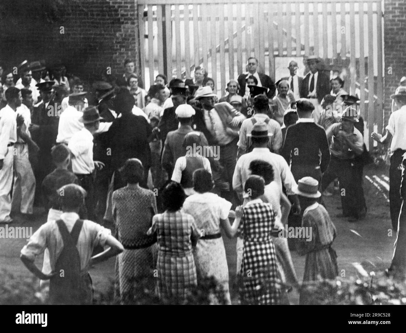 Macon, Georgia: 4 settembre 1934 la città di Macon Capo dei detective, T.E. Garrett al centro con un cappello bianco, si mette in un litigio con un operaio che colpisce, che si accovaglia alla destra e pronto per il combattimento. Si trovano di fronte allo stabilimento della Bibb Manufacturing Company Foto Stock