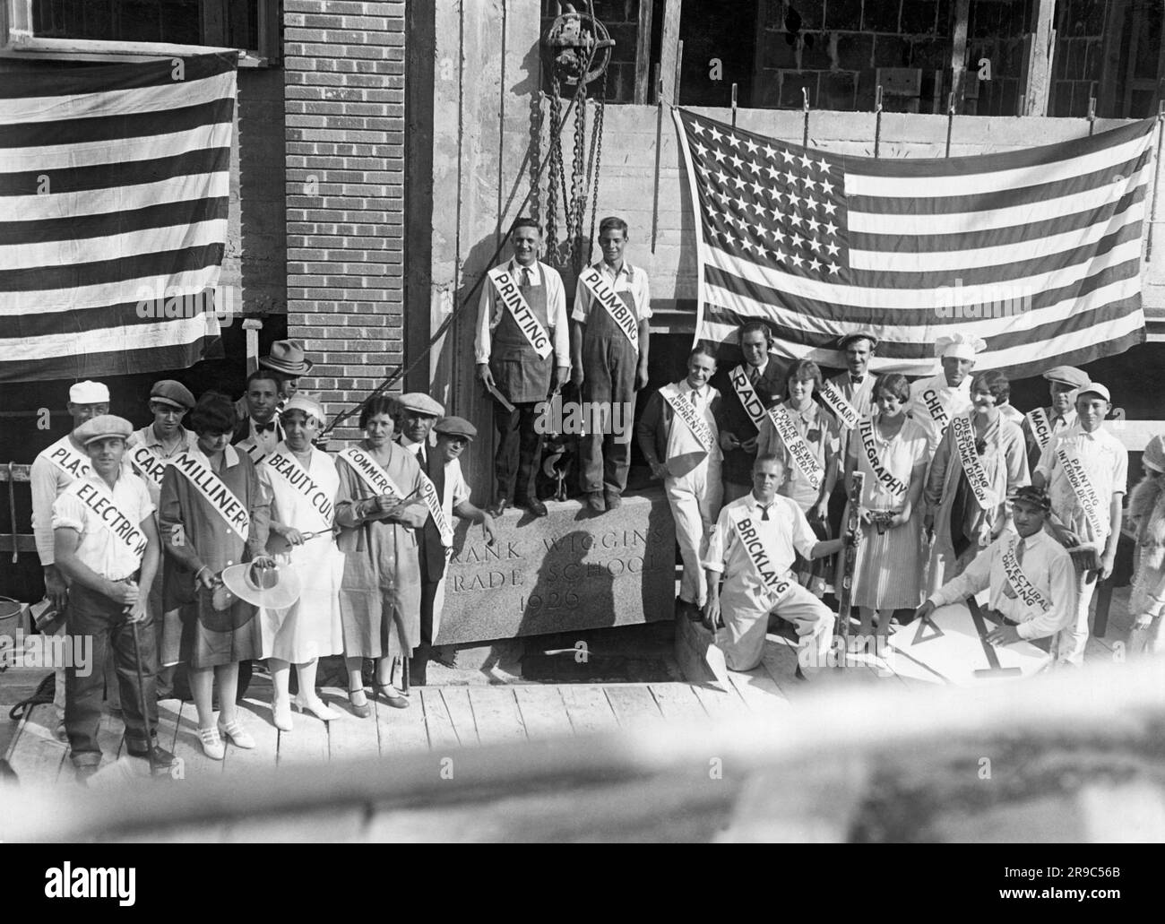 Los Angeles, California: 1926 la dedica della nuova Frank Wiggins Trade School al 1646 South Olive St Ha fornito formazione per l'elettricità, l'intonaco, le macchine, il falegname, la verniciatura, cultura della bellezza, commercio, stampa, idraulica, muratura, radio, operatore di macchine da cucire a motore, schede di presentazione, telegrafia, sartoria, disegno architettonico, chef/cucina, macchinari e decorazioni per interni. I rispettivi rappresentanti detengono gli strumenti del loro commercio. Foto Stock