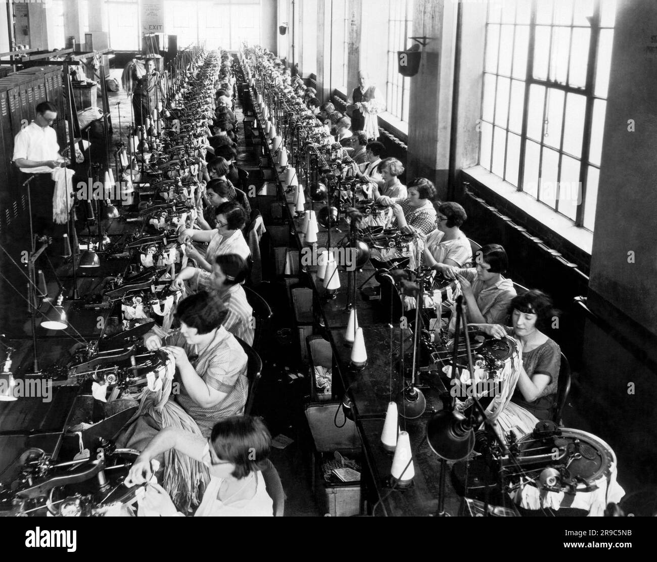 Philadelphia, Pennsylvania: 1922 circa una scena in una fabbrica di pelletteria di seta femminile. Le donne stanno lavorando sulle macchine per cucire che cucono la cucitura sul retro della calza. Foto Stock