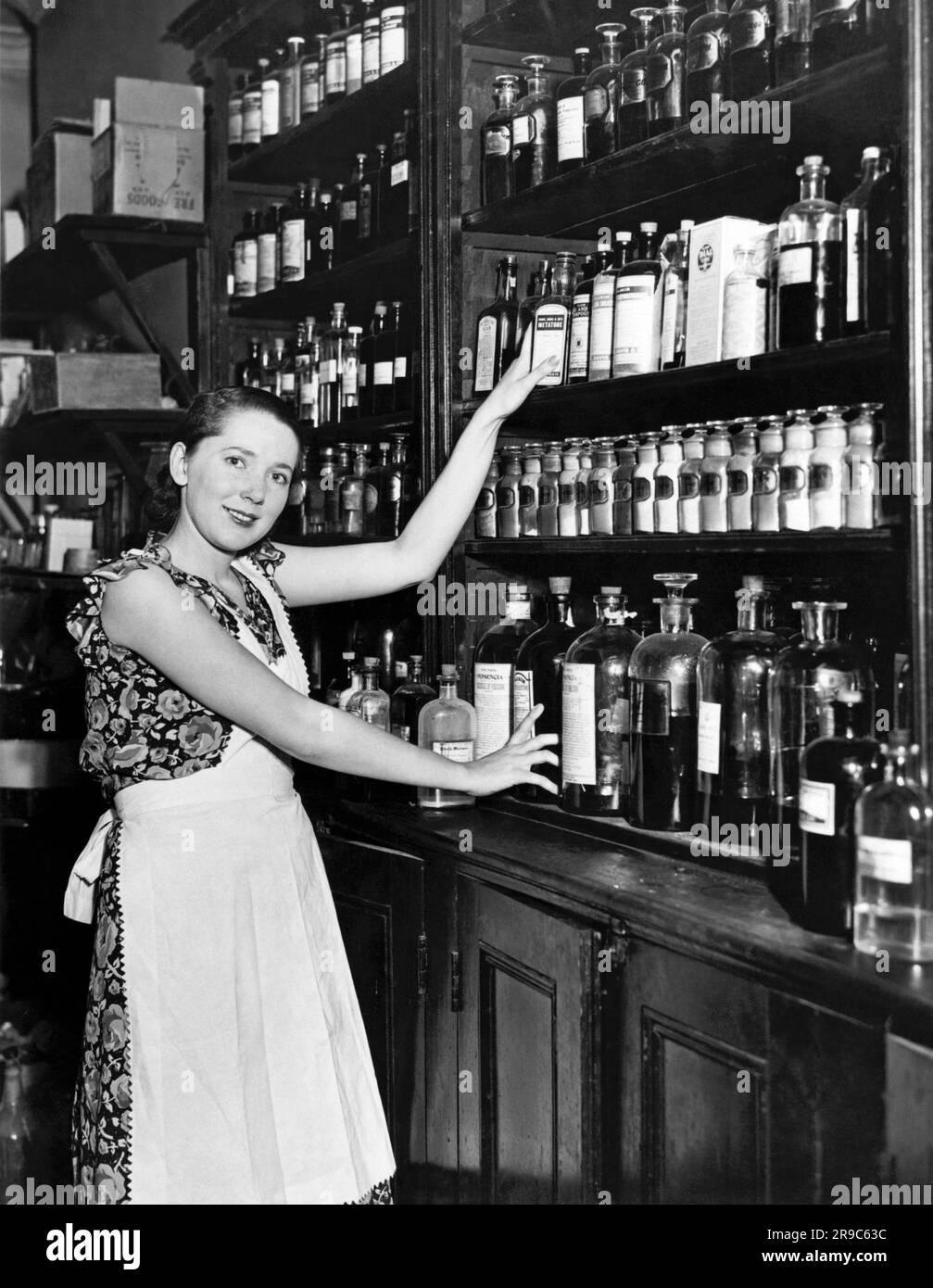 New York, New York: 1929 Marie Bard, 22 anni, che è la modella del poster della Croce Rossa del 1930 e del francobollo statunitense illustrati dall'artista Lawrence Wilbur. Non fuma, non resta sveglia fino a tardi, e cucina e pulisce per sua madre, un farmacista, e suo padre, un importatore di caffè e tè, ad Astoria, nel Queens. Qui sta aiutando sua madre in farmacia. Foto Stock