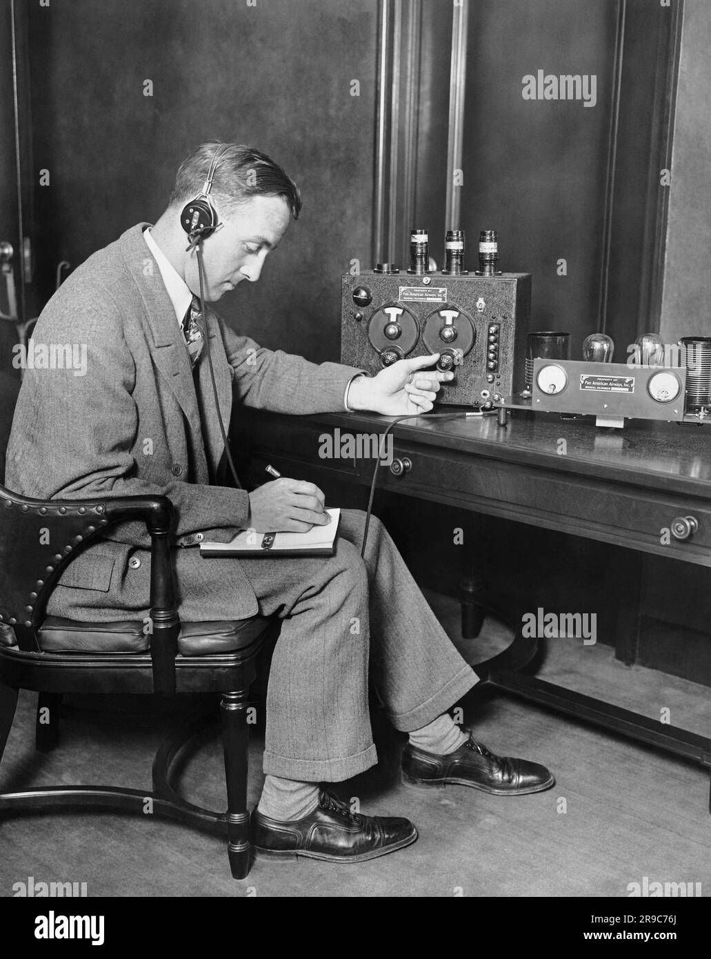 New York, New York: c. 1928 il responsabile delle comunicazioni della Pan-American Airways dimostra il dispositivo wireless bidirezionale ad alta frequenza che ha perfezionato per la comunicazione tra piloti e stazioni di terra. Foto Stock