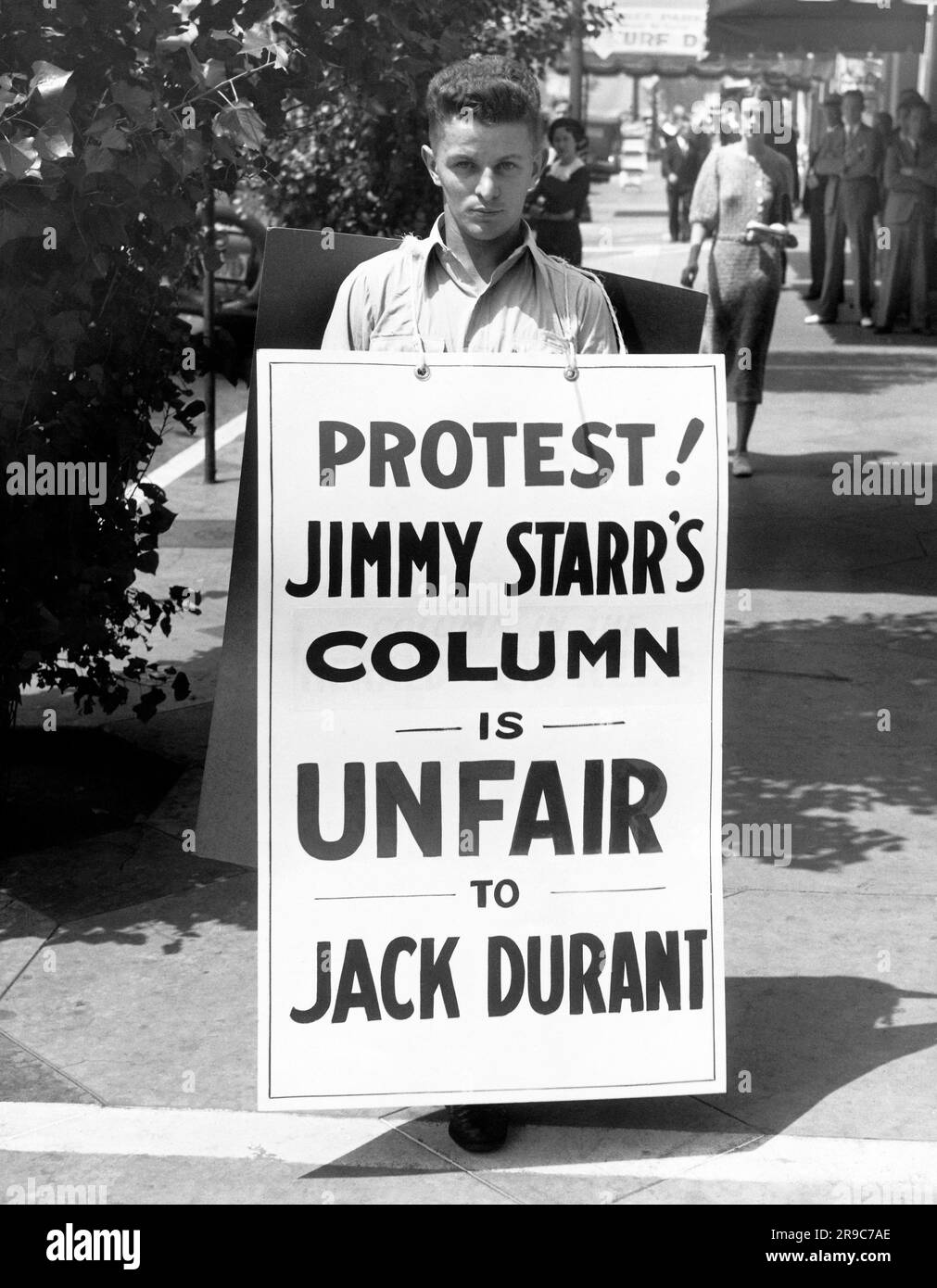Hollywood, California: c. 1936 l'attore Jack Durant cammina con una paninoteca protestando contro il suo trattamento in una colonna di Jimmy Starr. Foto Stock