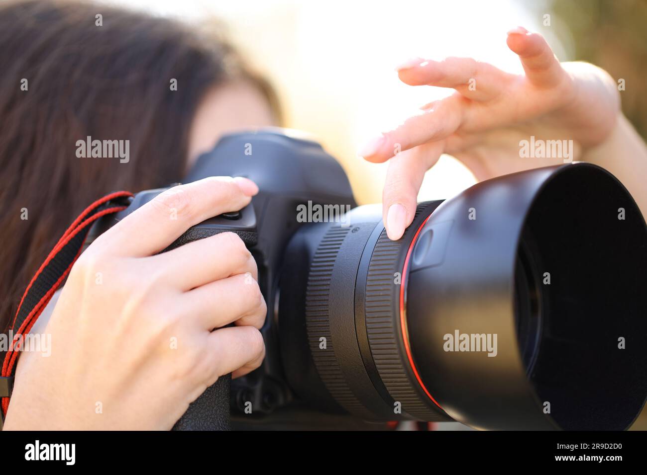 Ritratto ravvicinato di un fotografo con la mano regolando la messa a fuoco manualmente per scattare foto all'aperto Foto Stock