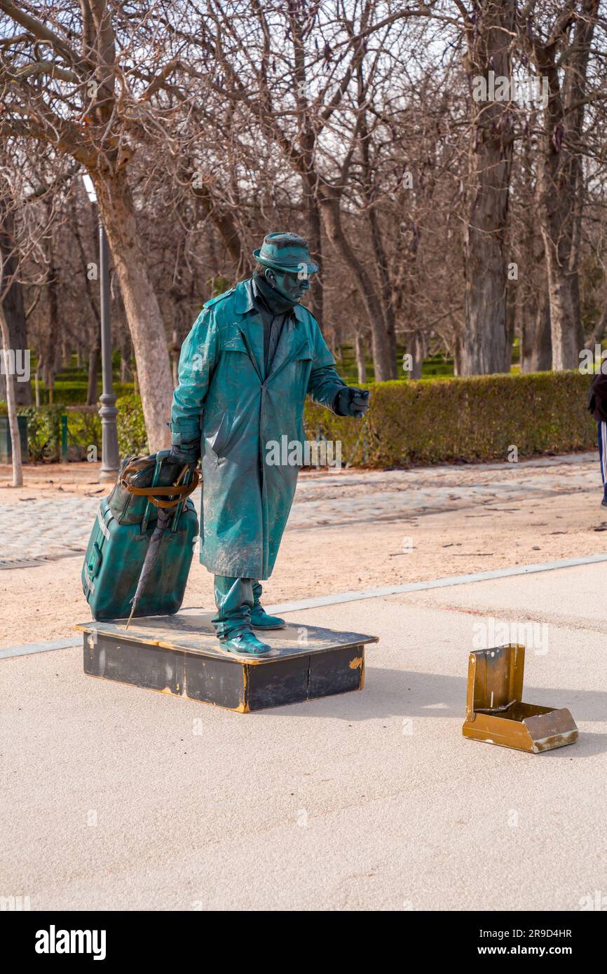 Madrid, Spagna - FEB 16, 2022: Artista maschile che esegue una mostra di statue umane che si comporta come una statua di bronzo di un uomo che porta borse, Parco del Buen Retiro, Madrid. Foto Stock