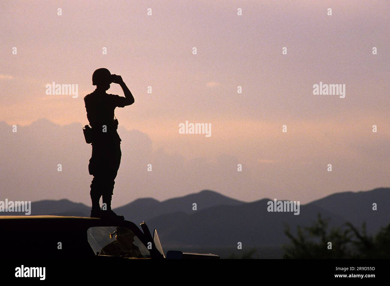 Soldato in piedi sulla sommità del camion osservando l'area circostante con il binocolo durante l'allenamento a ft. Bliss, El Paso, Texas. Foto Stock