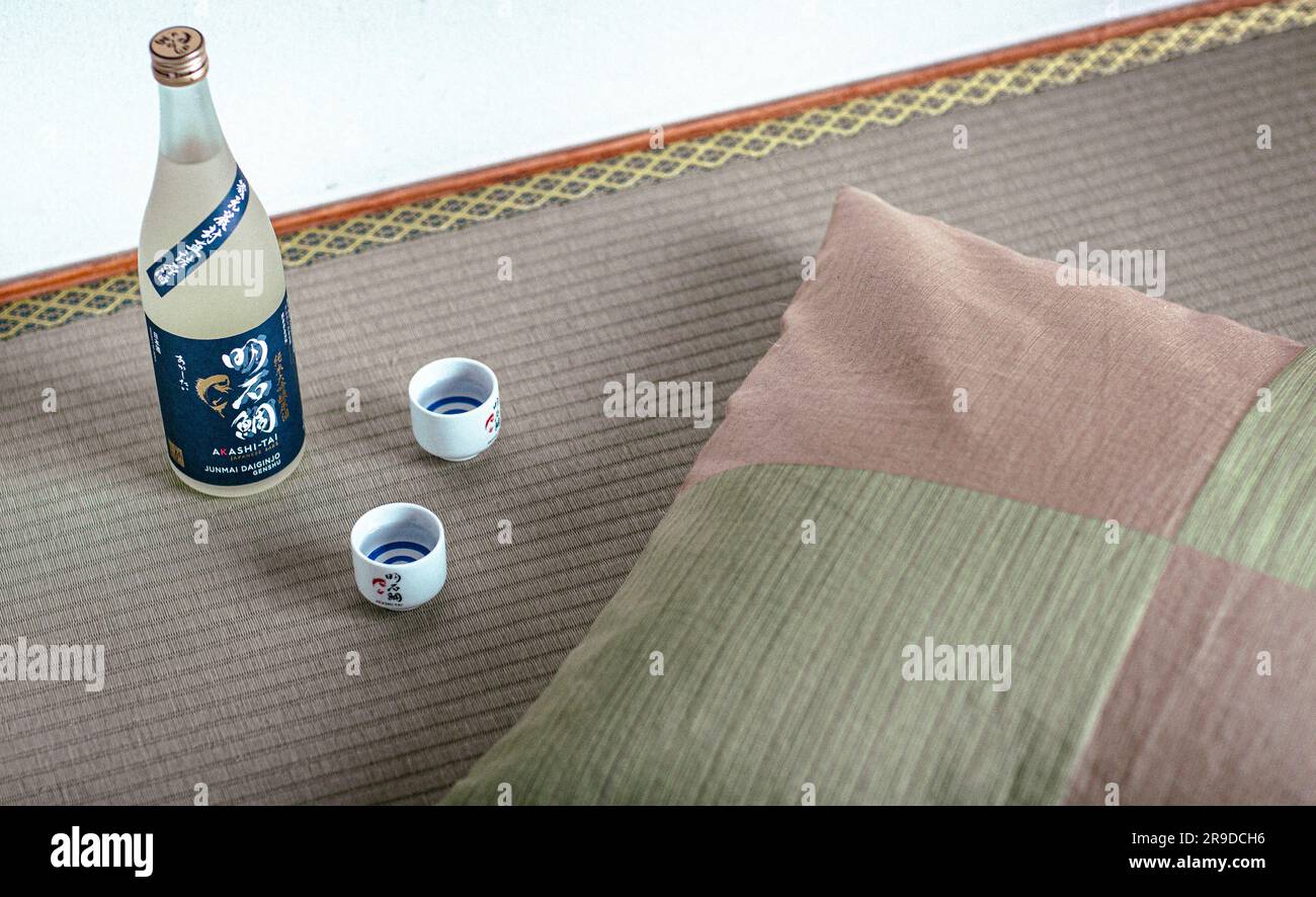 tazze di sake e bottiglia sul pavimento della camera tatami opaca, il sake è un liquore giapponese a base di riso fermentato. Foto Stock