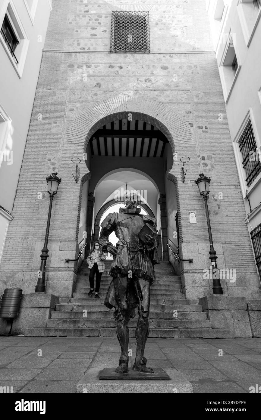 Toledo, Spagna-FEB 17, 2022: Statua di Cervantes presso l'Arco de la Sangre, storica porta araba della città, ex Bab-al-Yayl nella vecchia città imperiale di Foto Stock